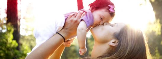 Billede af en kvinde som holder og kysser en baby.W