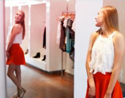 Billede af en pige, der står foran et spejl og prøver tøj.